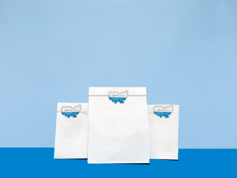 Specialty medication packaged with white paper bag, sticker in a blue background