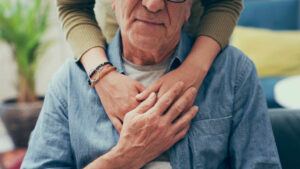 Una persona consolando a un anciano.