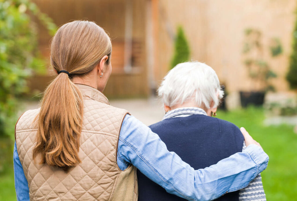 A carer walking with an elderly person in a park