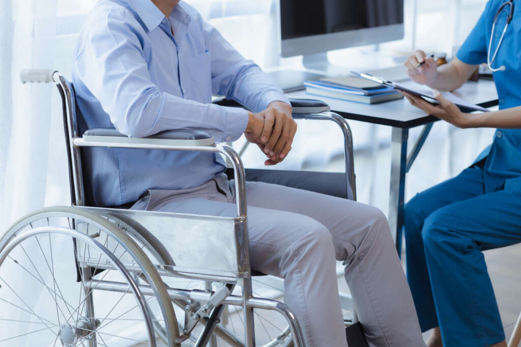 A person sitting in a wheelchair comforted by a doctor