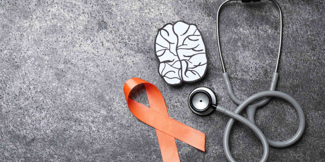 Orange ribbon, stethoscope and paper brain cutout for multiple sclerosis awareness