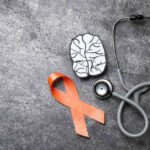 Orange ribbon, stethoscope and paper brain cutout for multiple sclerosis awareness