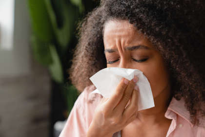 Woman with runny nose suffering from Kevzara side effects