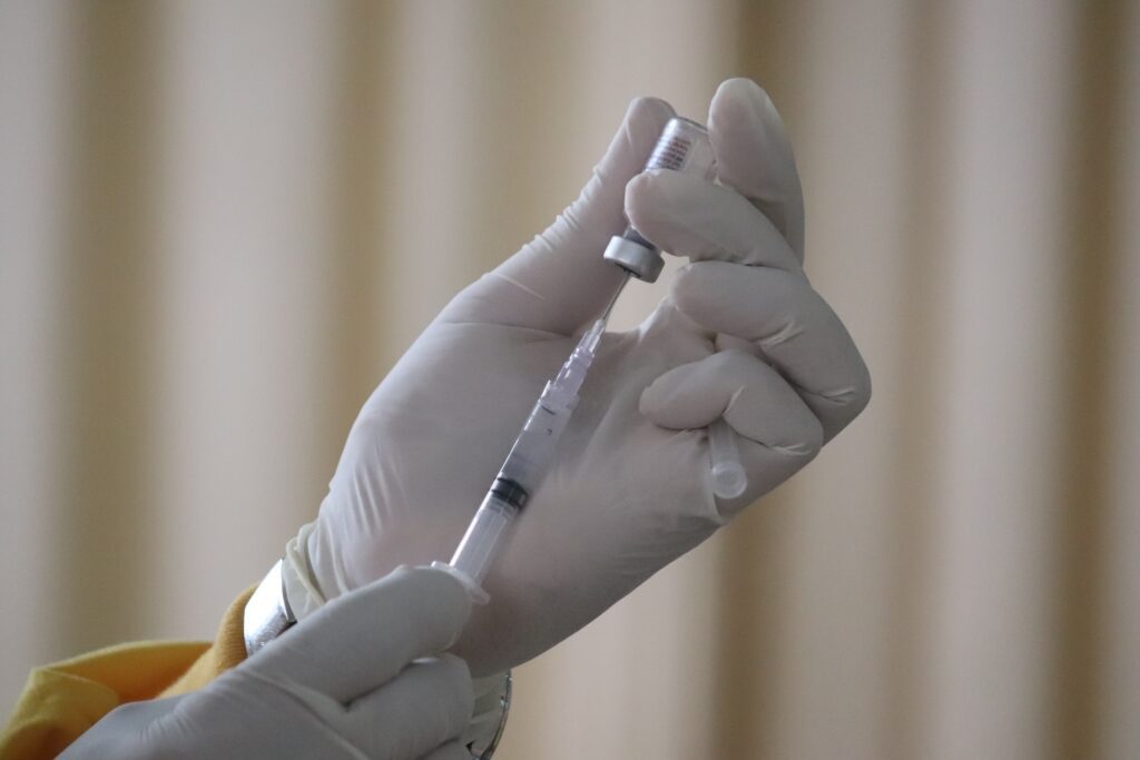 A person holding a syringe and a vaccine vial