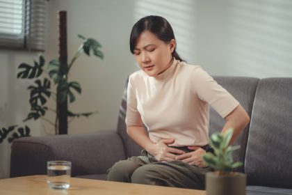 Asian woman feeling stomachache as a side effect of Reblozyl