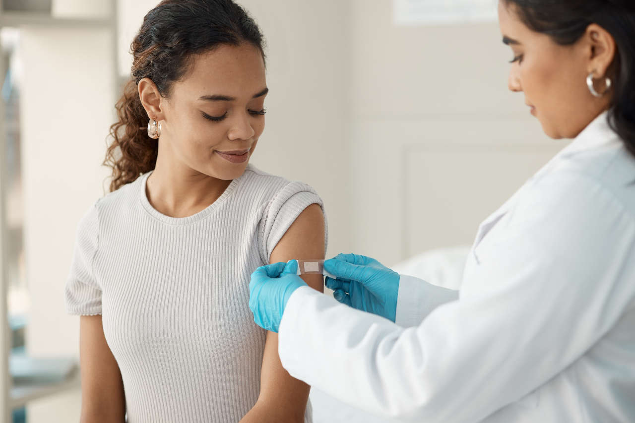 Young doctor applying a band-aid to patient following a vaccine injection