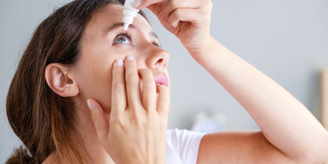 Young woman putting in eye drops for autoimmune uveitis