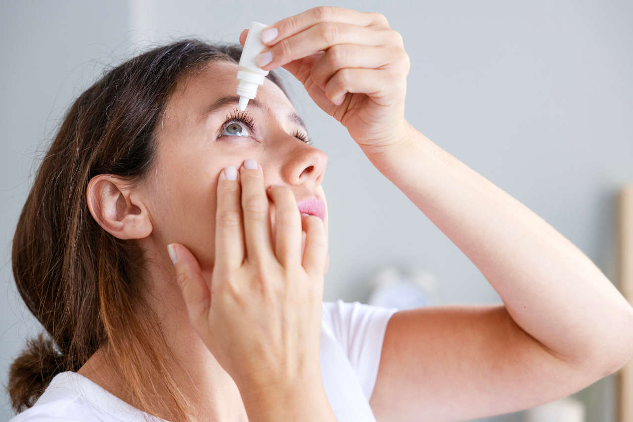 Young woman putting in eye drops for autoimmune uveitis