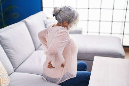 Middle aged grey-haired woman suffering for back pain