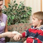 Home healthcare nurse bandaging child with hemophilia
