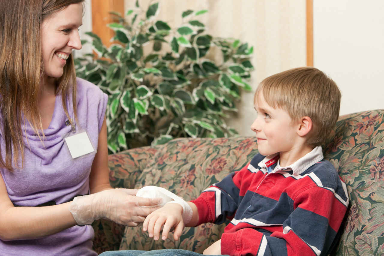 Home healthcare nurse bandaging child with hemophilia
