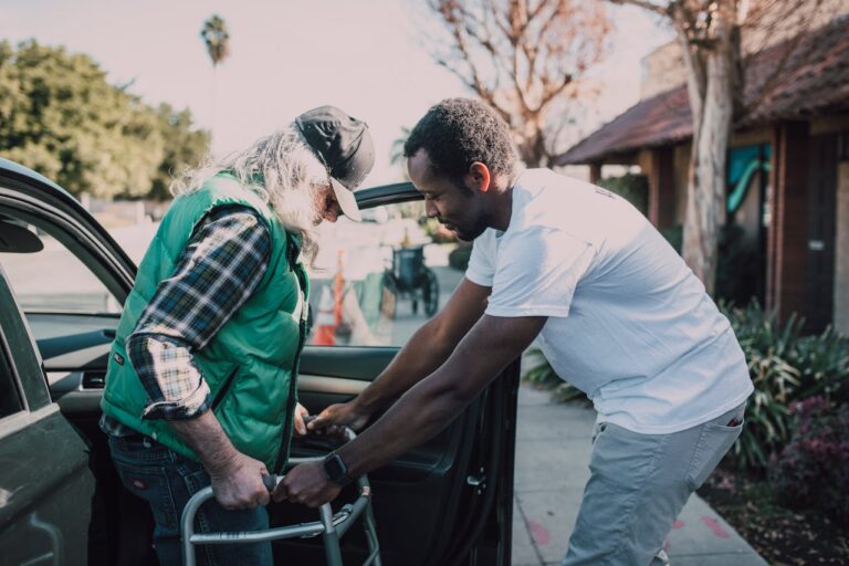 Man helping patient on walker get out of car