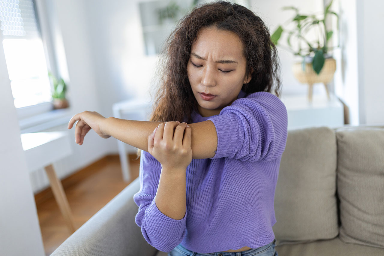 A woman sitting on a couch holding her elbow in pain