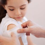 Girl with hemophilia receiving bandage on arm