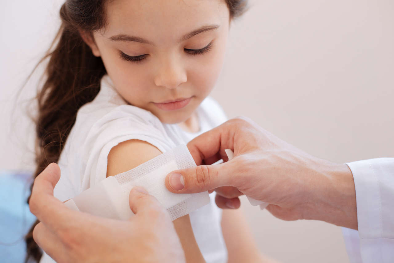 Girl with hemophilia receiving bandage on arm