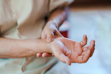 An elderly woman squeezing her wrist due to pain from rheumatoid arthritis