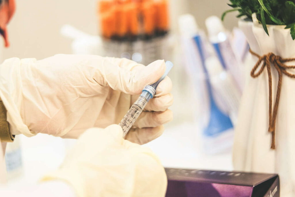 A gloved hand filling a syringe