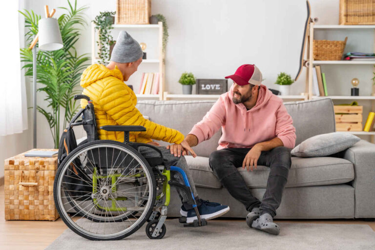 Man with ALS in a wheelchair talking to friend