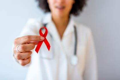 Doctor holding red ribbon for HIV awareness