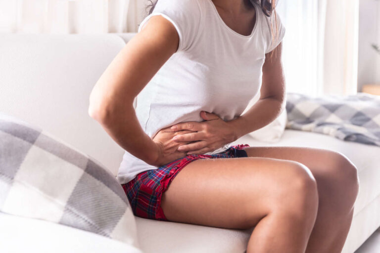 Woman on a couch suffering from symptoms of IBD