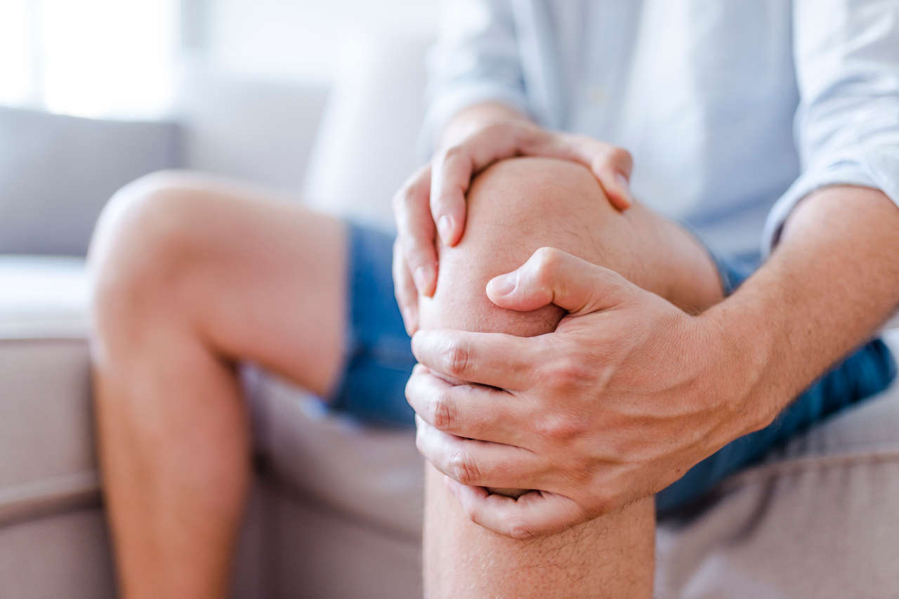 Man holding knee that has joint pain as a result of hemophilia