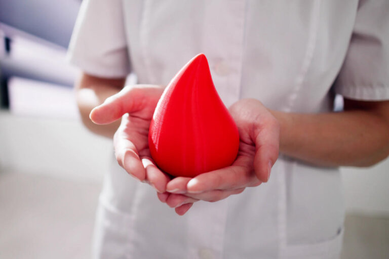 Doctor holding plastic blood drop for hemophilia awareness in women