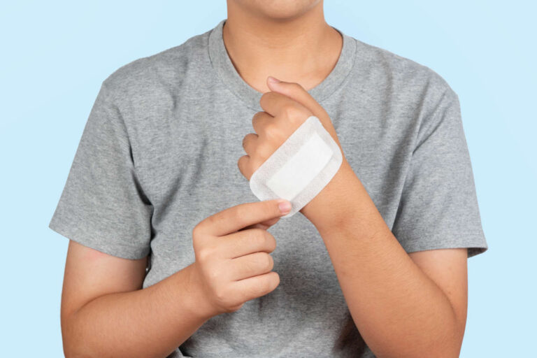 Hemophilia patient putting adhesive bandage on hand