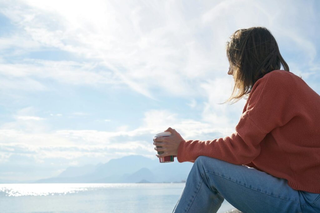 A woman sitting in front of a beach