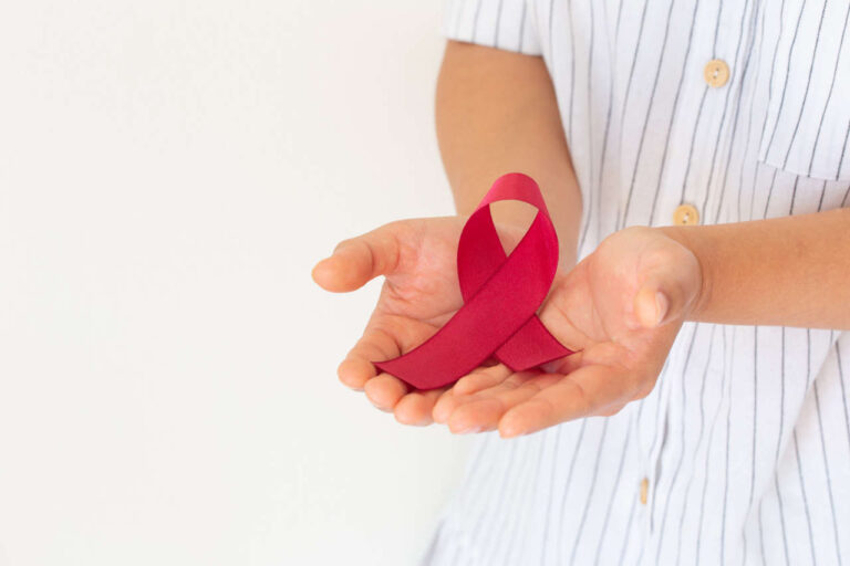 Hands holding red, burgundy ribbon for multiple myeloma awareness