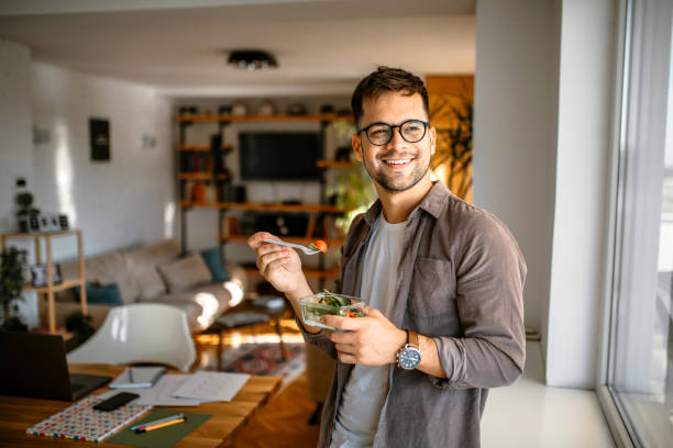 Man eating salad in living room