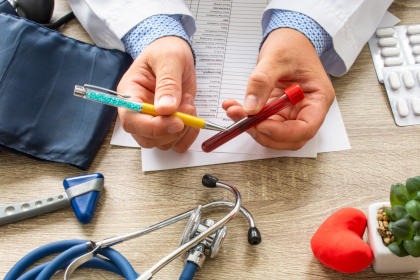 A doctor pointing to a blood sample tube with his pen