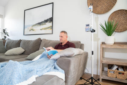 Man sitting on sofa in living room while receiving IVIG therapy