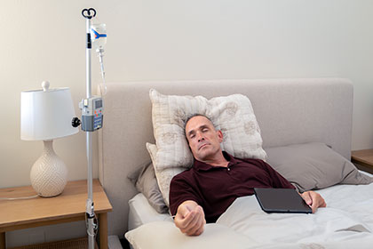 Man in bed at home receiving IVIG therapy for acquired red cell aplasia