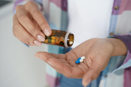 Patient pouring prescription pills into their hand