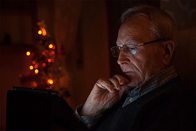 An older man with glasses looking at his tablet