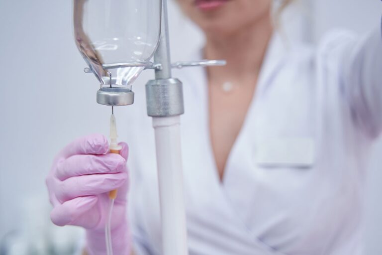 A nurse injecting a solution into an IV bag