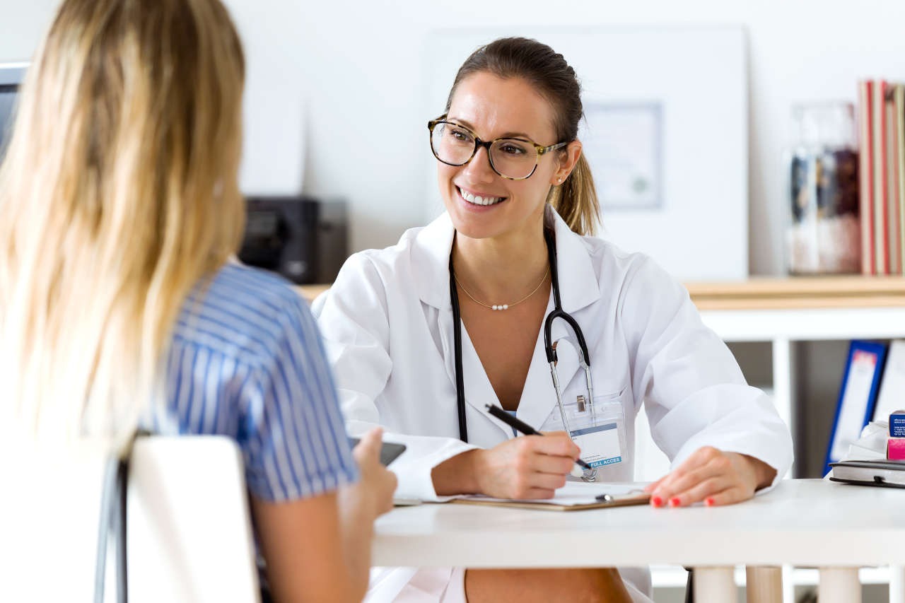 A smiling doctor listening to a patient and taking notes