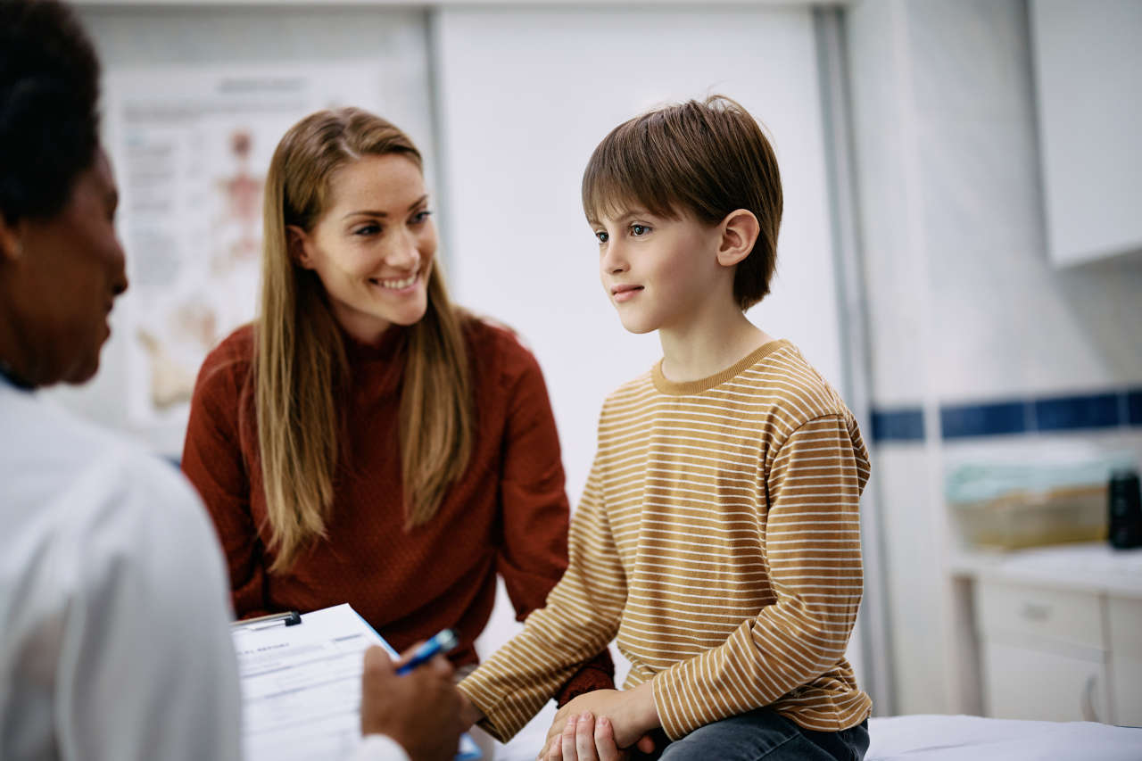 Boy with hemophilia discussing free drug program for hemophilia with doctor