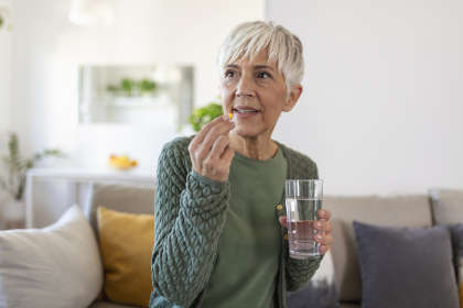 A senior woman taking a tablet of Ojjaara