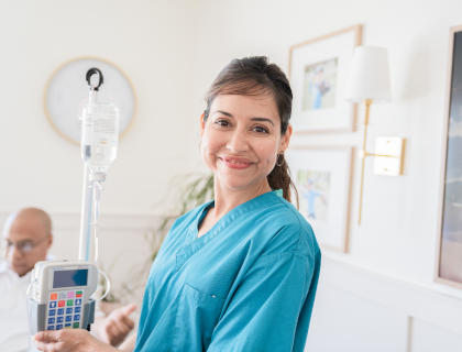 Smiling IVIG nurse standing next to an IV pole