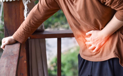 Patient leaning over and holding stomach, experiencing abdominal pain