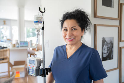 IVIG nurse standing next to a pole  set up with an IVIG bottle and a pump