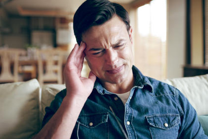 Man with headache suffering from symptoms of long COVID
