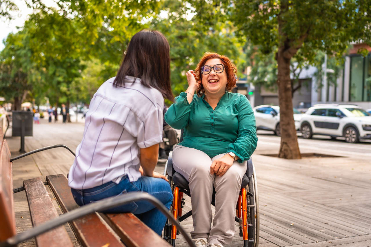 MS patient who takes cladribine in a wheelchair talking to a friend