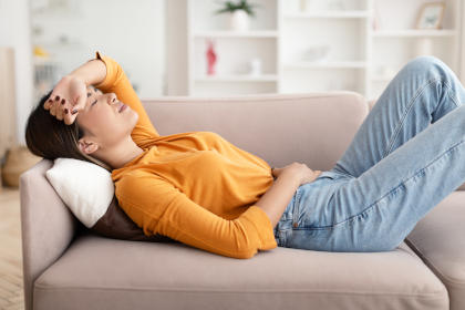 Woman lying on couch, suffering nausea as a result of taking lomustine