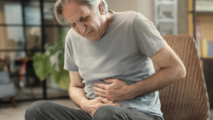 Man clutching stomach, experiencing abdominal pain after using Koāte-DVI