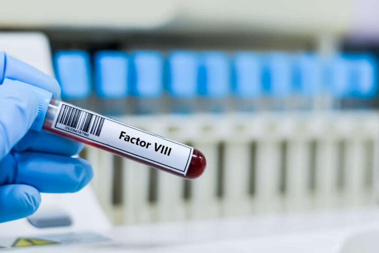 Gloved hand holding test tube with Factor VII, which gets replaced when a patient uses Koāte
