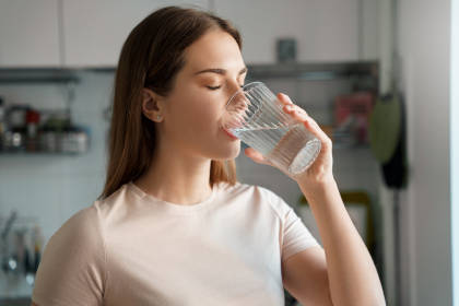 Woman drinking water after experiencing thirst, a common side effect of tolvaptan