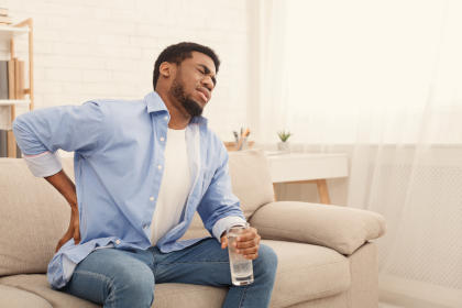 Man experiencing back pain, a side effect of taking Alphanate sd